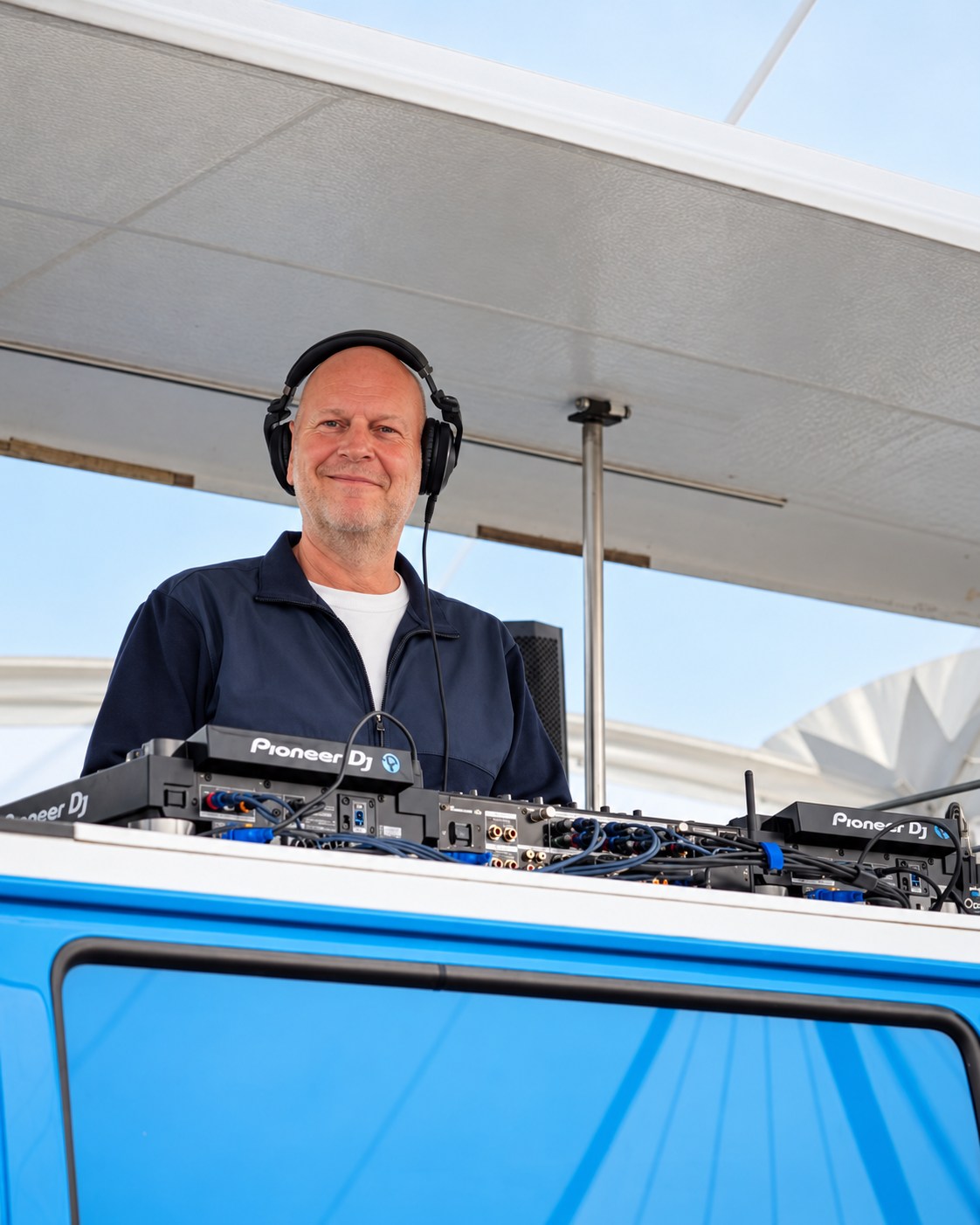 Etienne met koptelefoon achter een blauwe DJ-booth