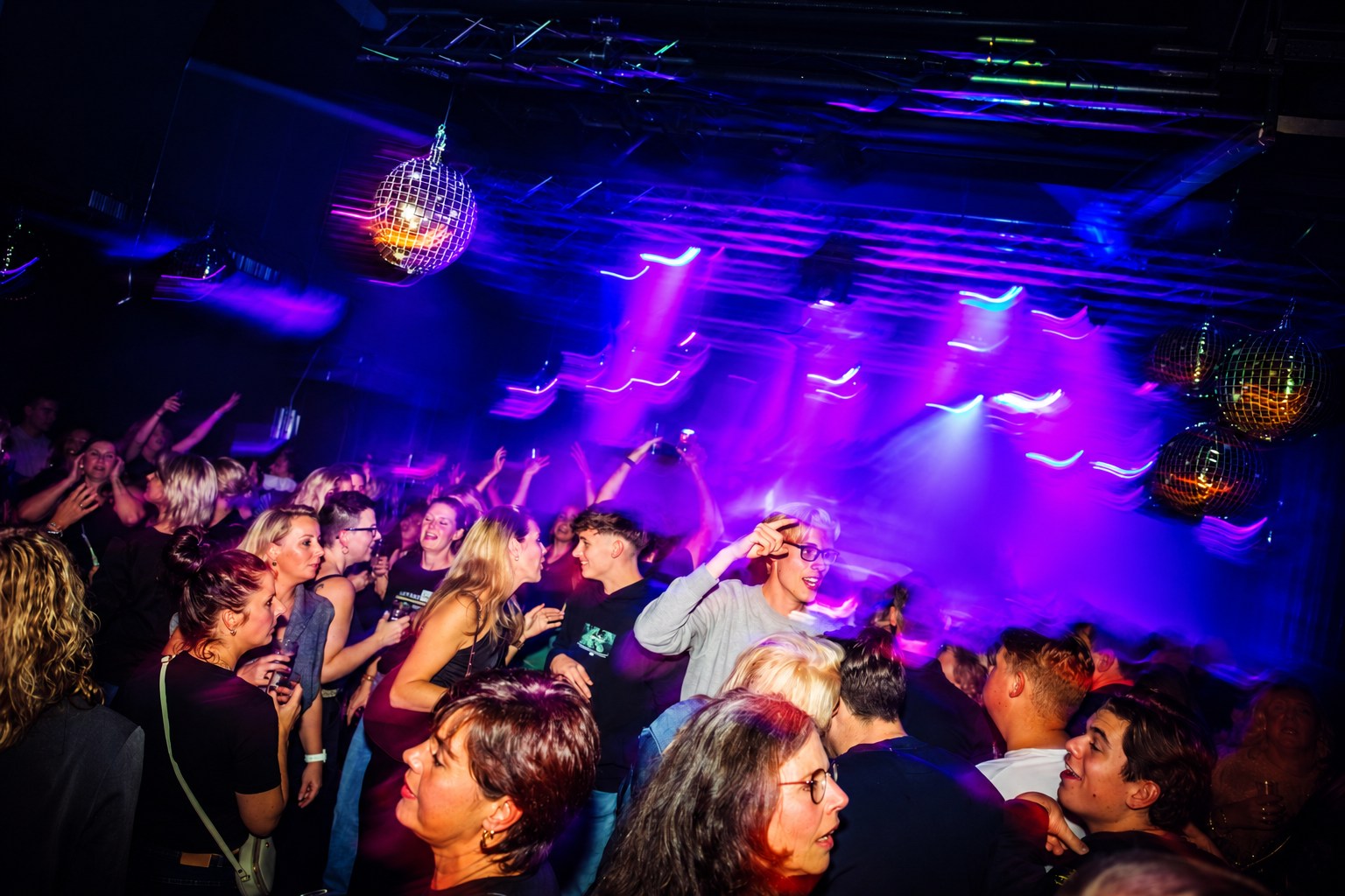 Een volle dansvloer met kleurrijke verlichting bij Lekker Dansen in 't Ukien